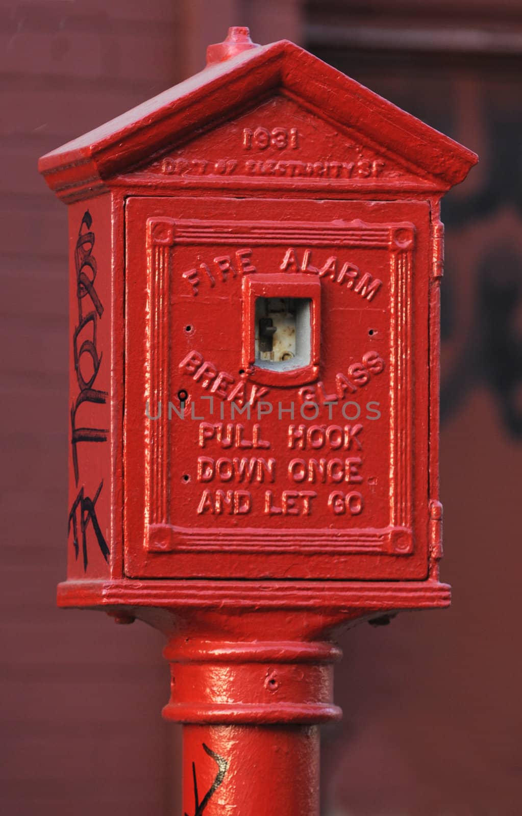 Old fire alarm switch on the street in an industrial area of San Francisco, vandalized with grafitti written on it