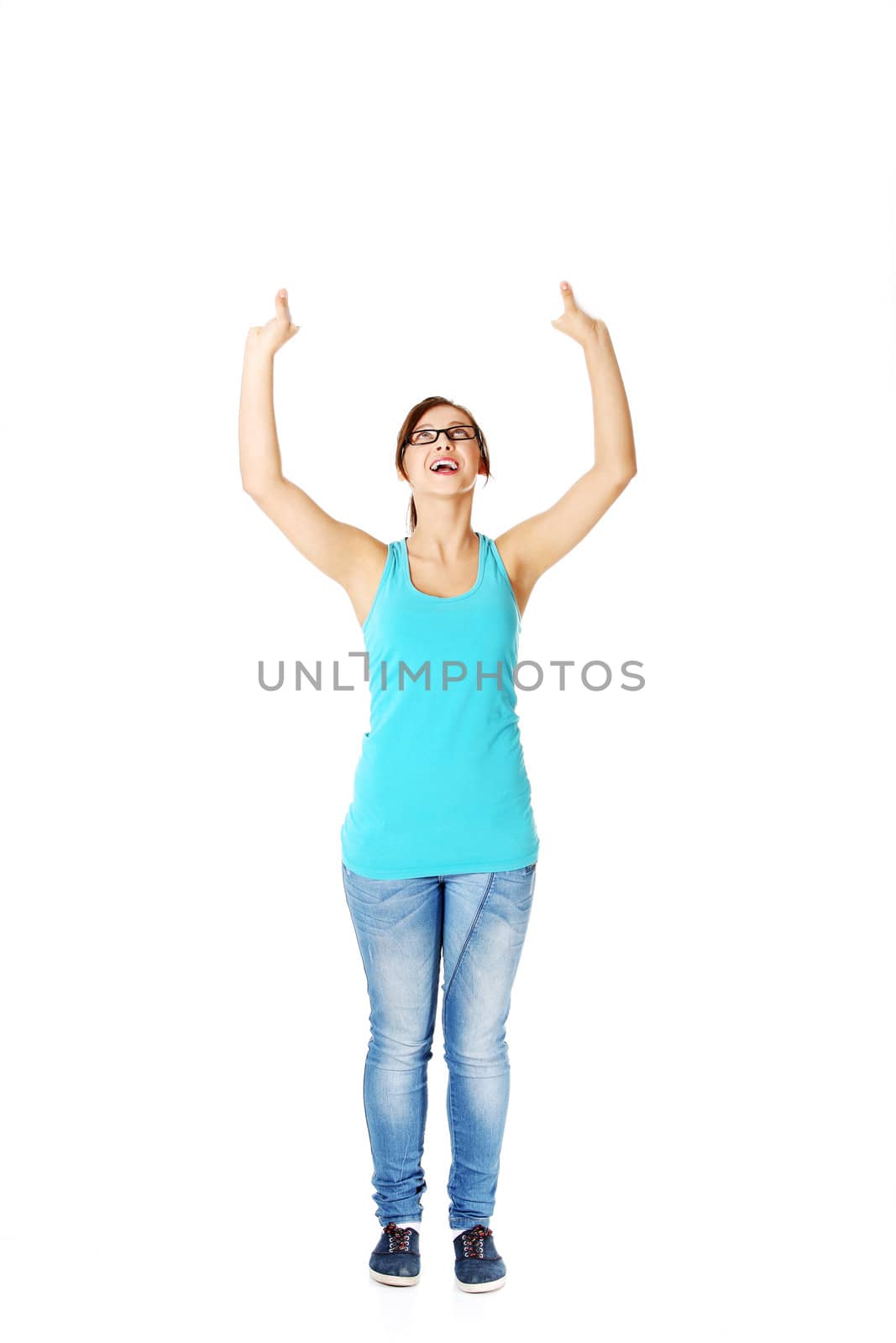 Young smiling girl in glasses holding sheet of paper in the air. Isolated on white.