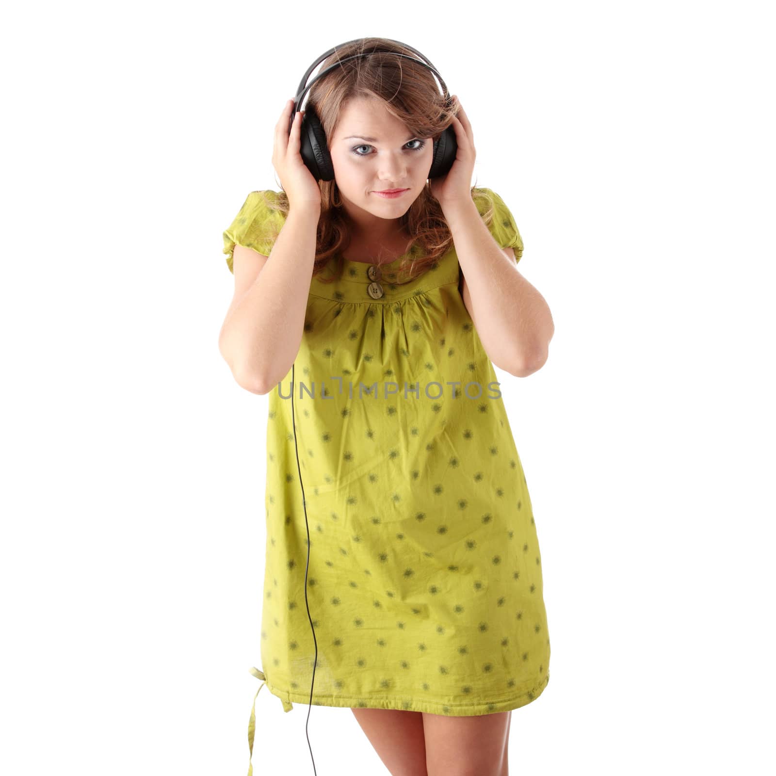 Beautiful teenage girl in a green dress listening to music with big headphones, isolated on white