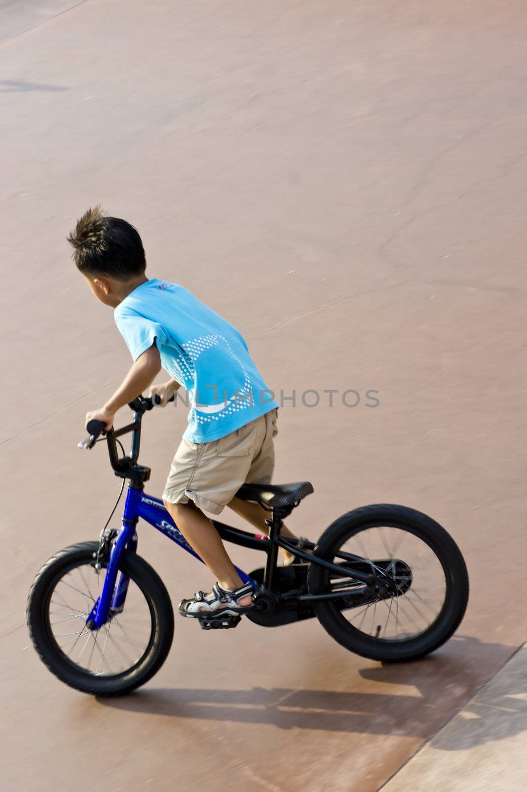 Asian Boy in blue standing up cycling 