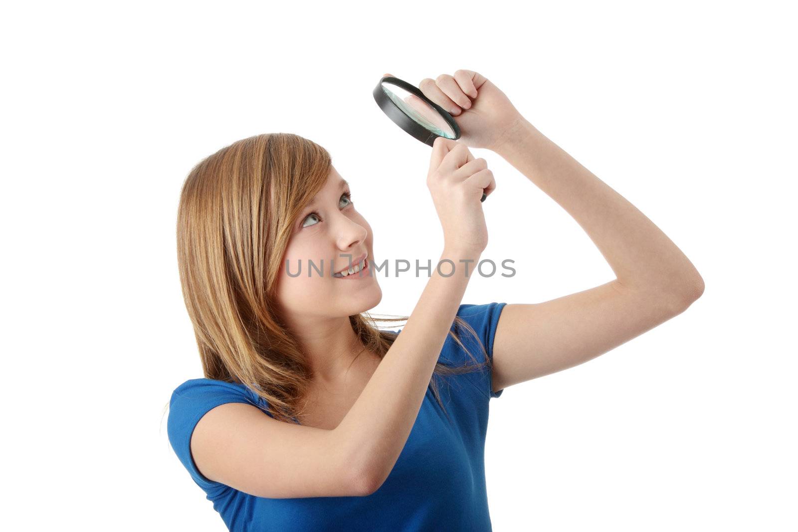 Young attractive smiling teen woman looking into a magnifying glass, isolated
