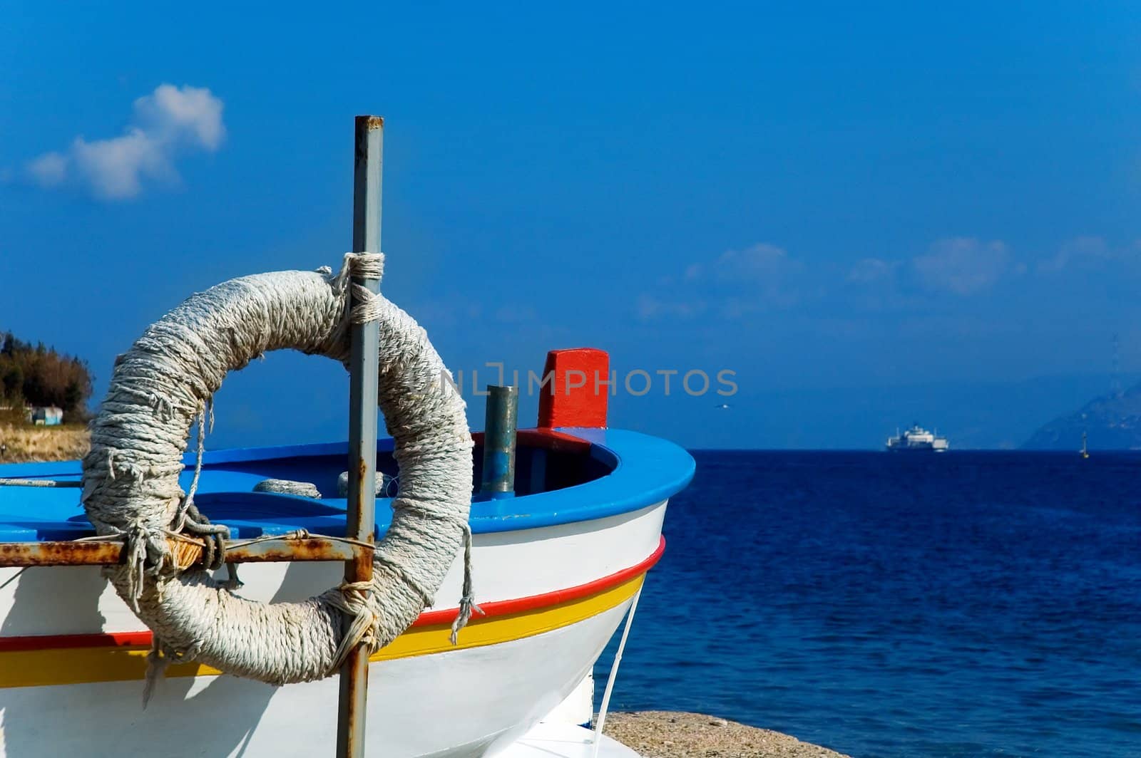 Fisherman boat overlooking Messina strait with sea and ship in the distance