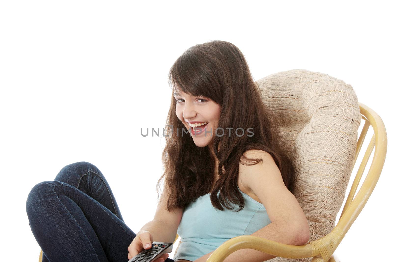 Teen woman watching TV with remote control while sitting on armchair view from TV
