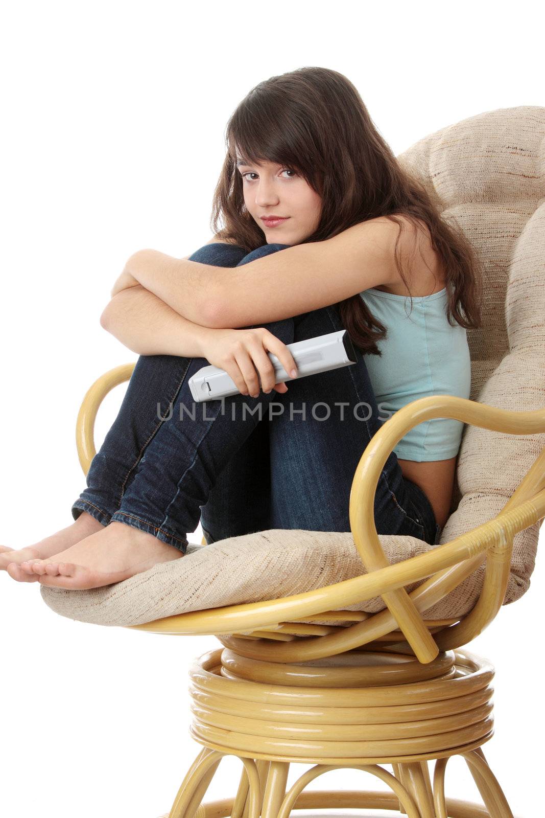 Teen woman watching TV with remote control while sitting on armchair view from TV