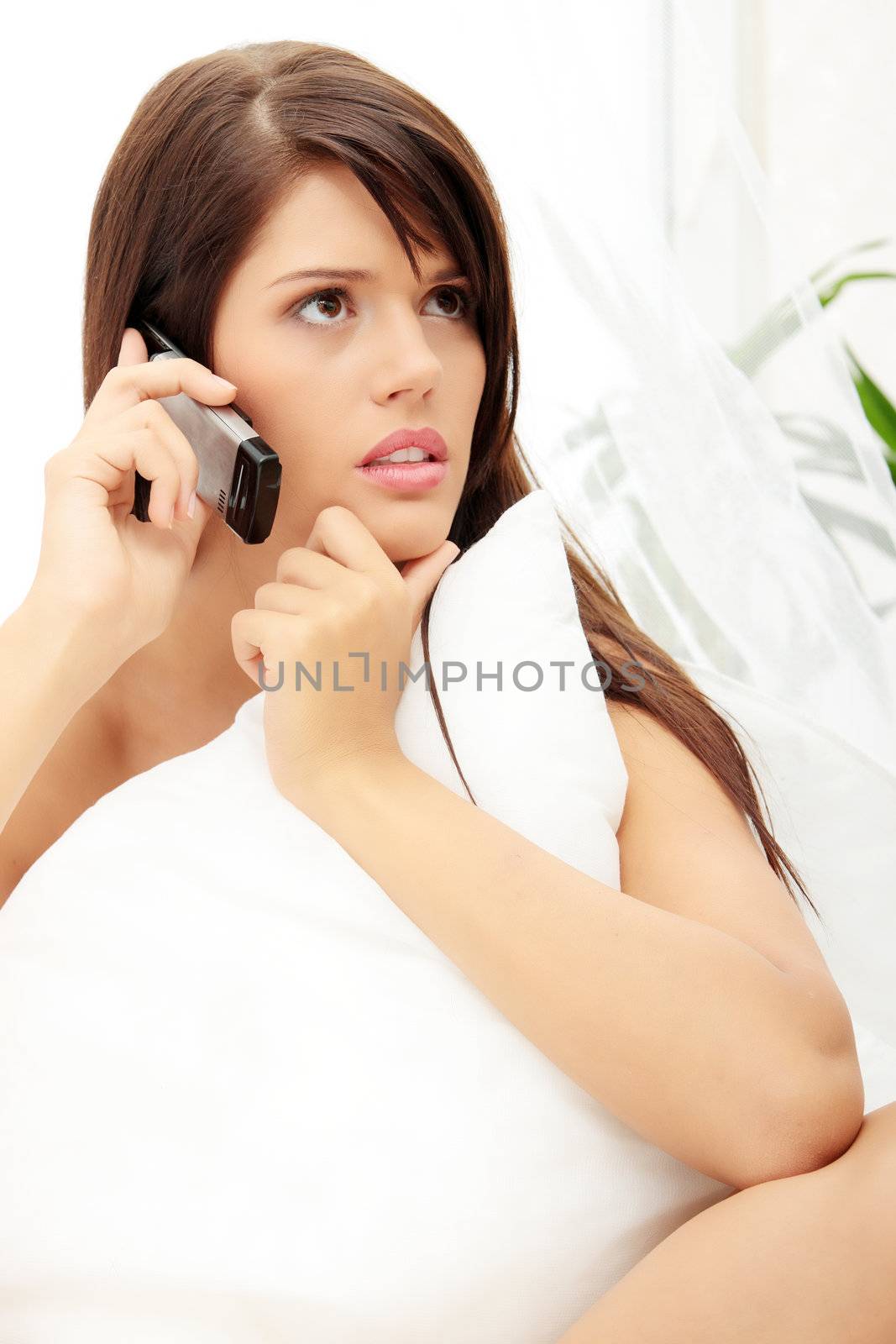 Pretty woman on phone lying on bed at home