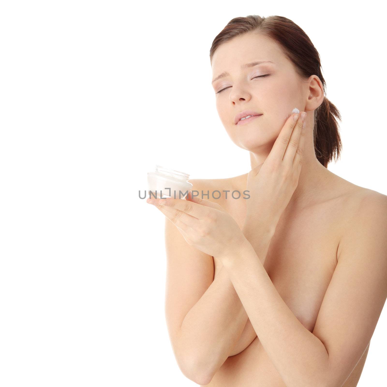 Woman applying moisturizer cream on face. Close-up fresh woman face.