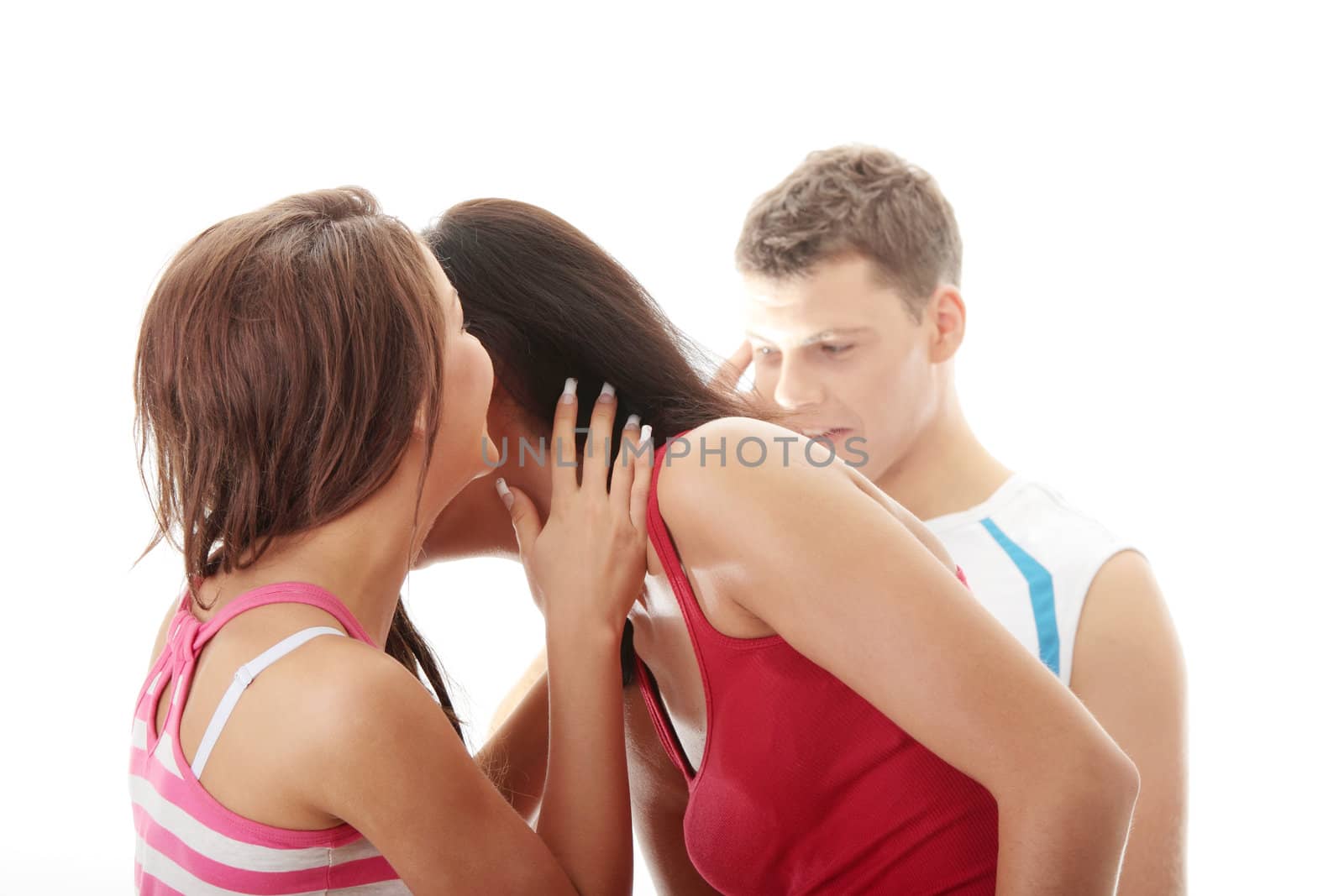 Two young women whispering about a man standing in background. Isolated on white