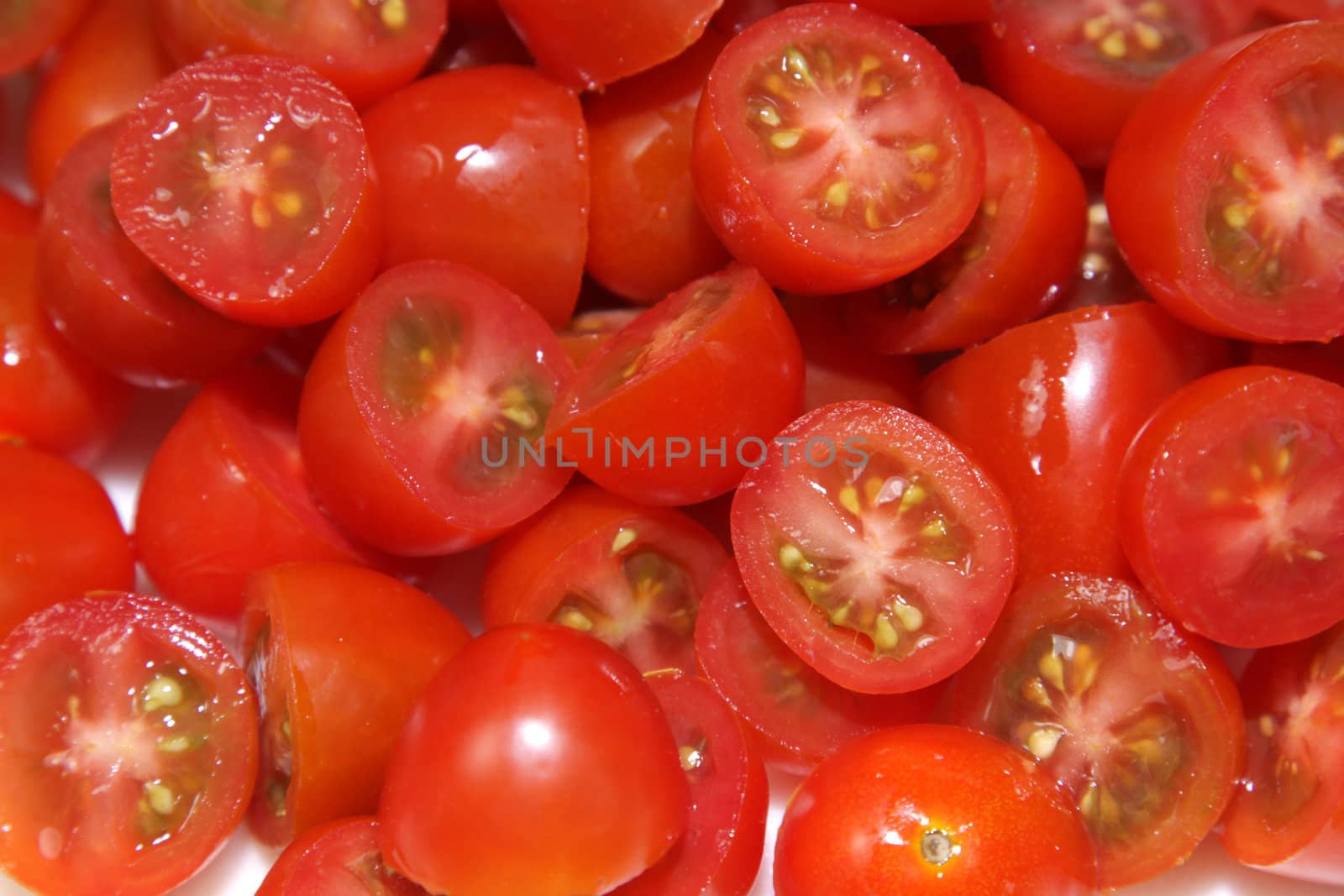 A pile of chopped of red cherry tomatoes.
