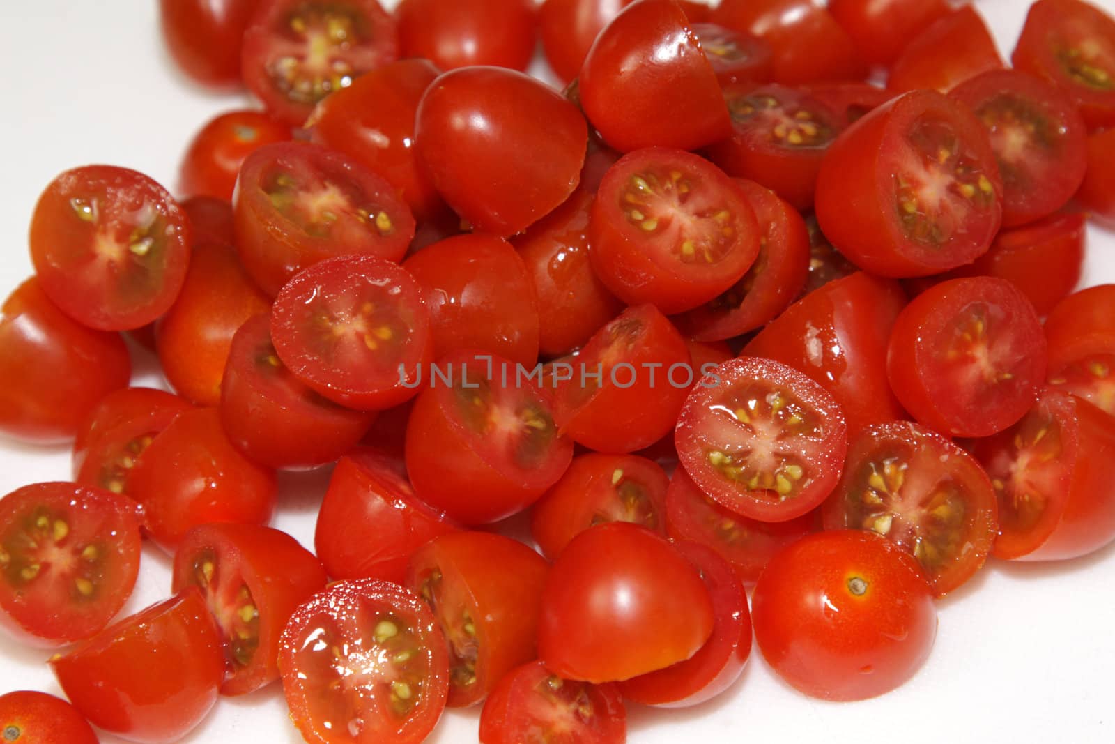 A pile of chopped of red cherry tomatoes.
