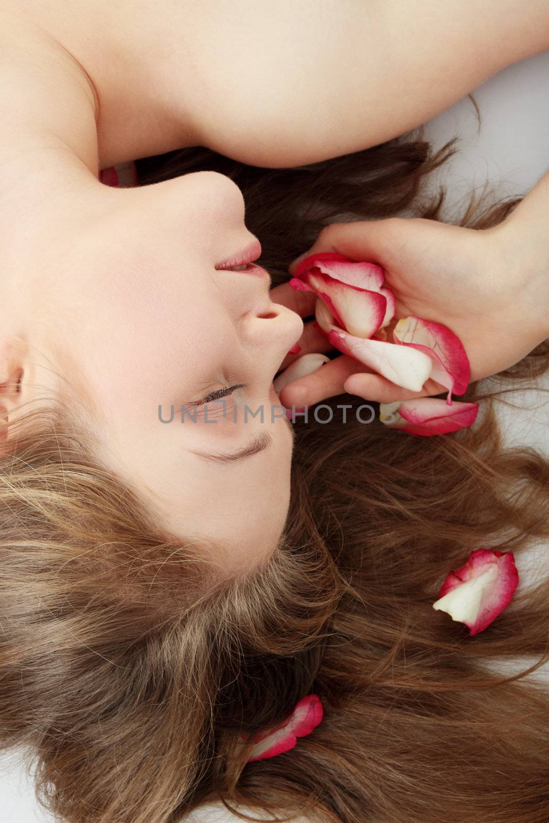 Close-up of beautiful young woman face with long blond hair and rose-petal