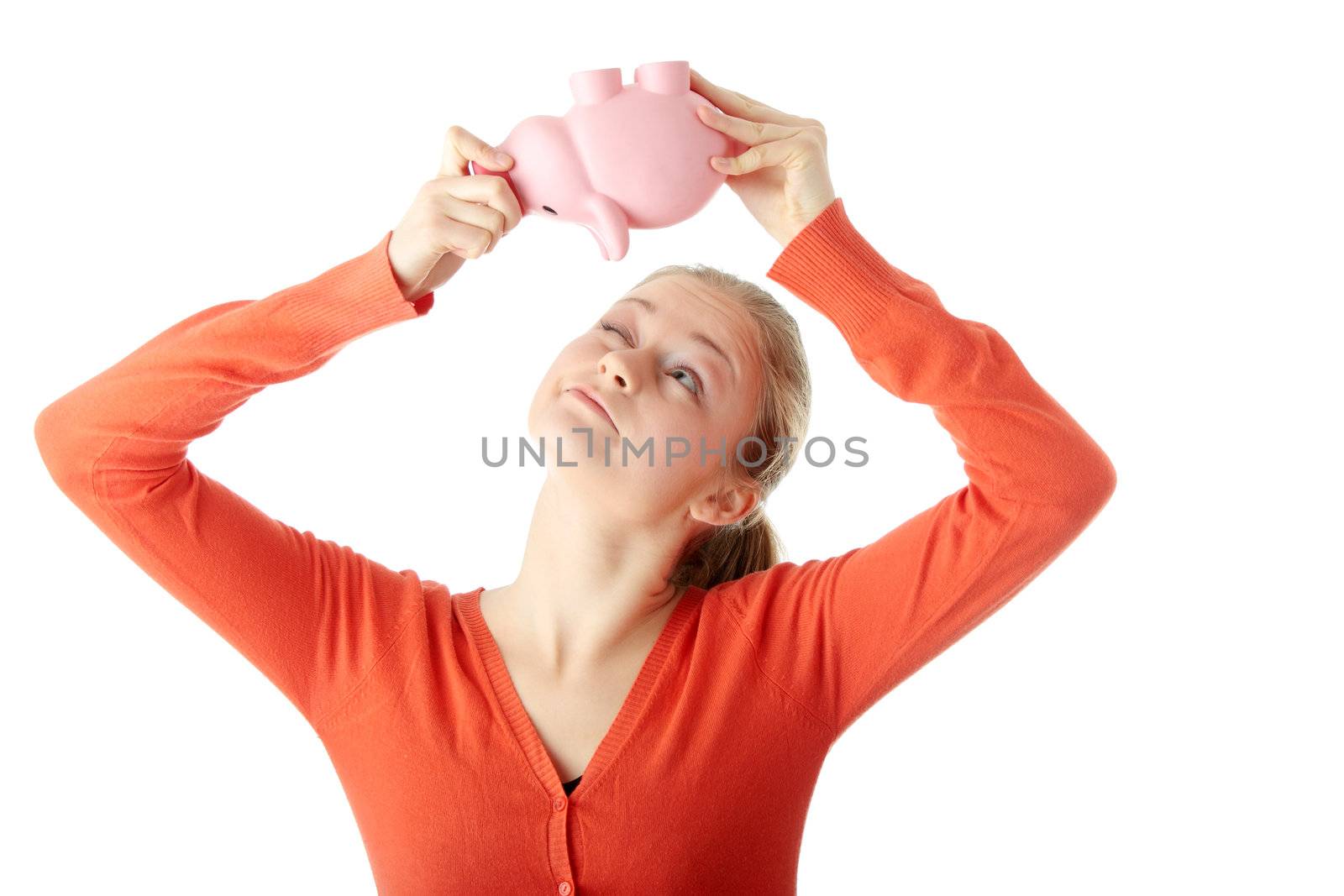 Young blond woman trying to get money from her piggy bank, isolated on white background