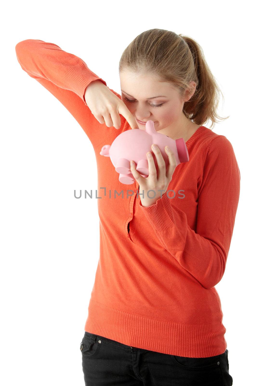 Young blond woman trying to get money from her piggy bank, isolated on white background