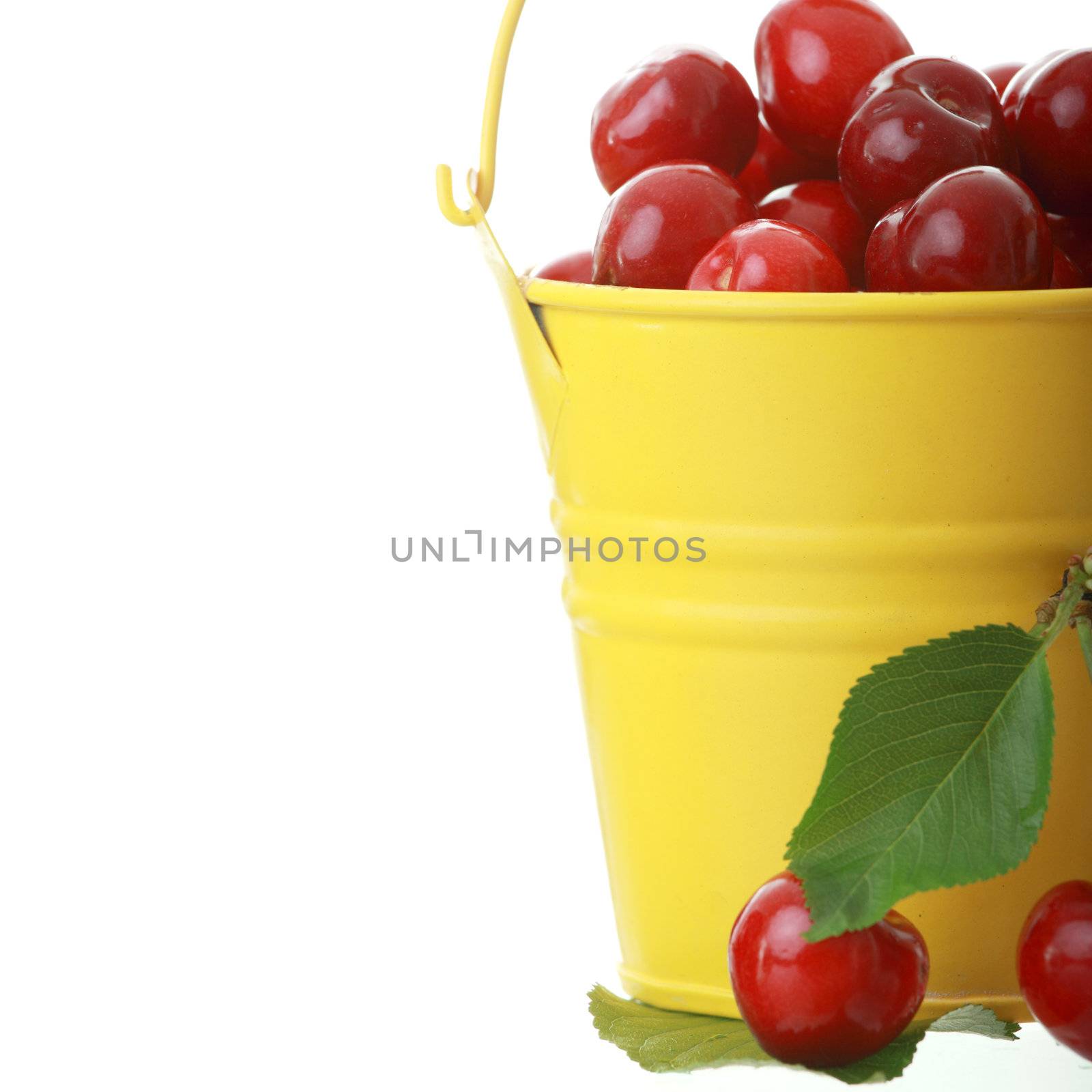 Cherries in colorful yellow metal bucket by BDS