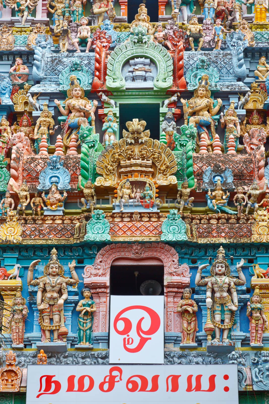 Sculptures on Hindu temple gopura (tower). Jambukeshwarar temple. Madurai, Tamil Nadu, India. Text in Tamil says "Om Namah Shivaya" mantra which means " I worship Shiva"