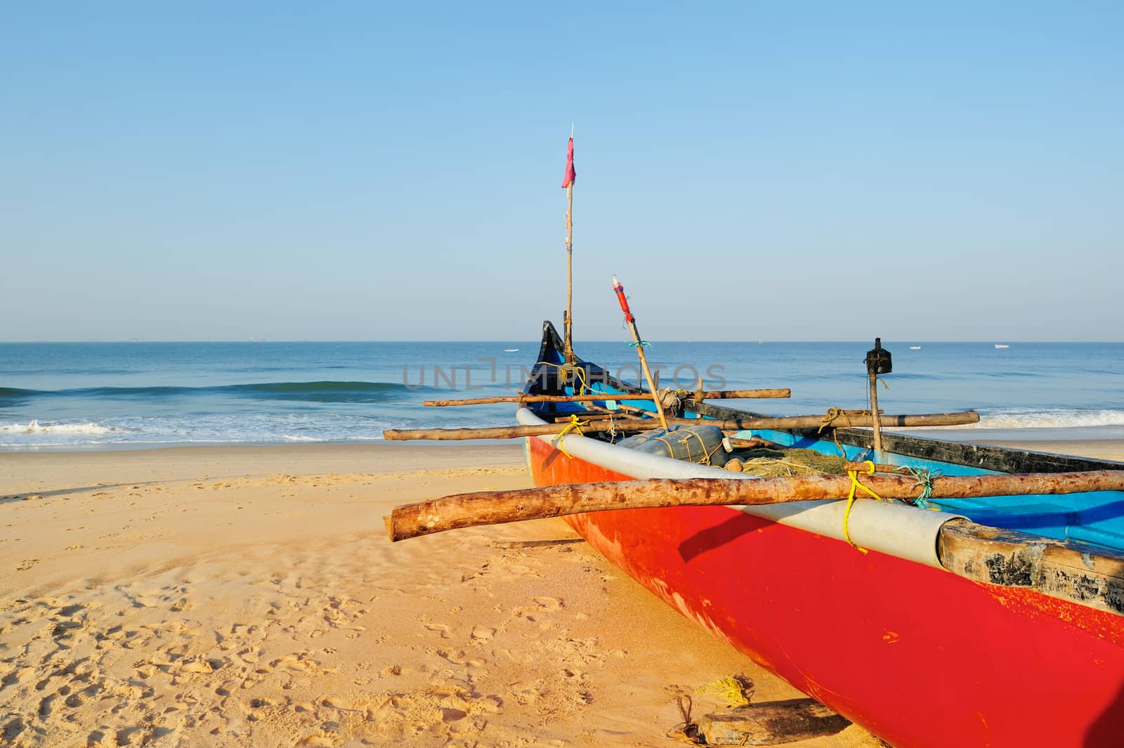 Red boat with fishing net on sandy shore