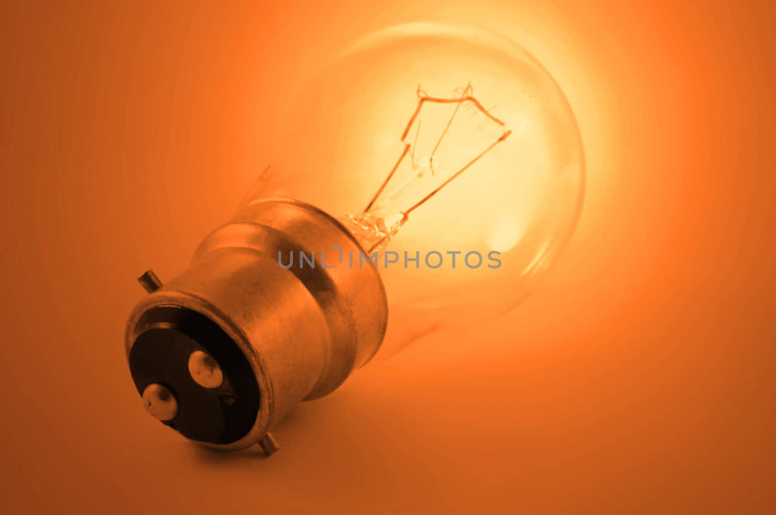 Close up of a single illuminated vibrant orange light bulb