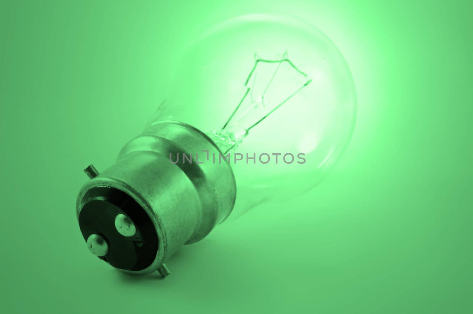 Close up of a single illuminated light bulb with green light effect