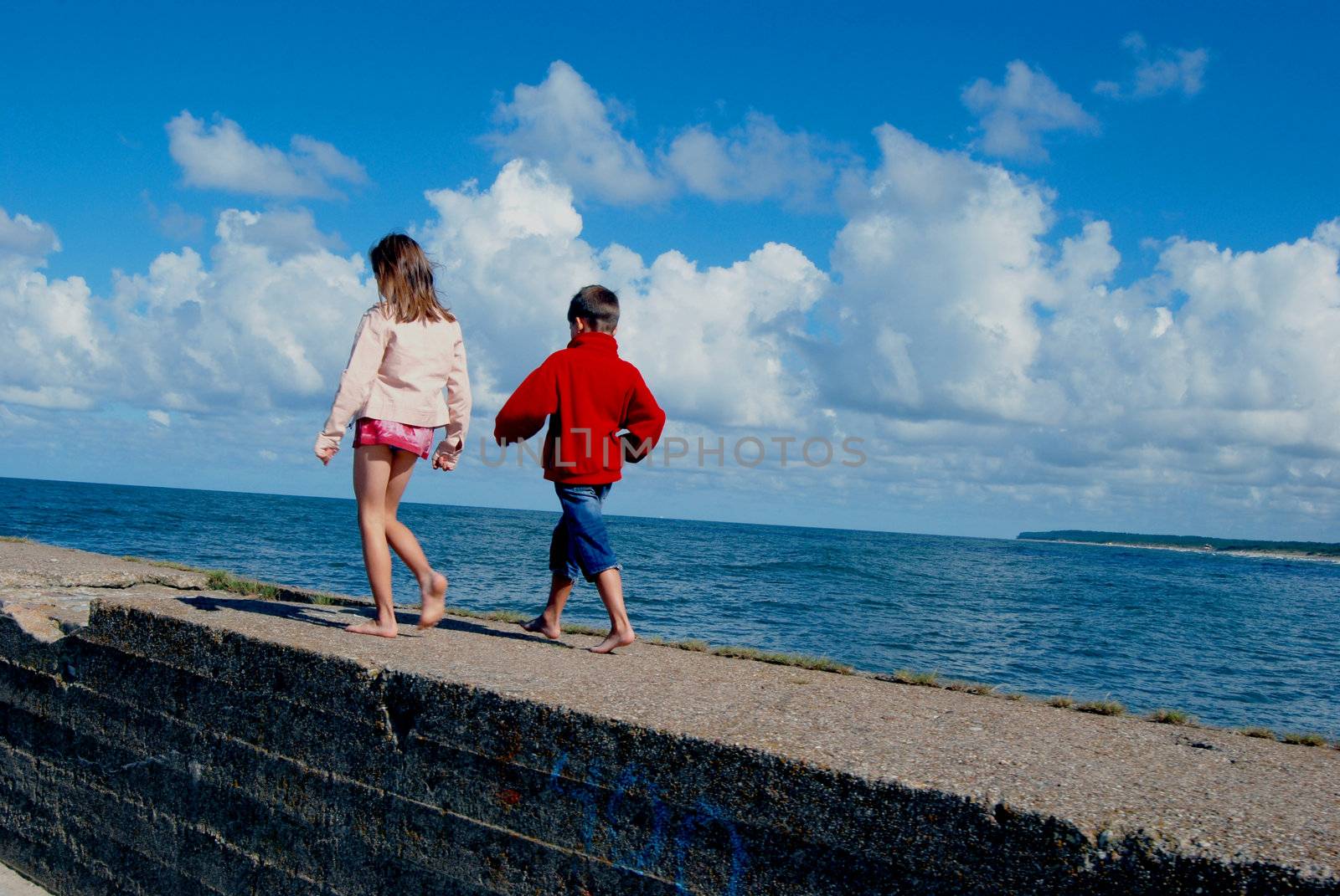 Boy and girl playing near the still sea