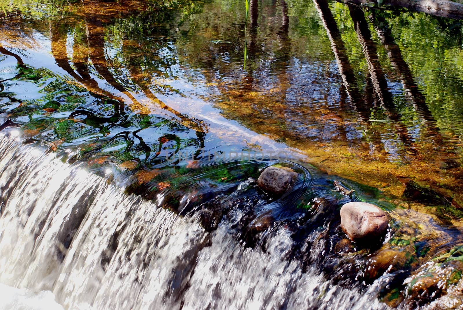 Wonderful river flow with little waterfall and beautiful reflections on water