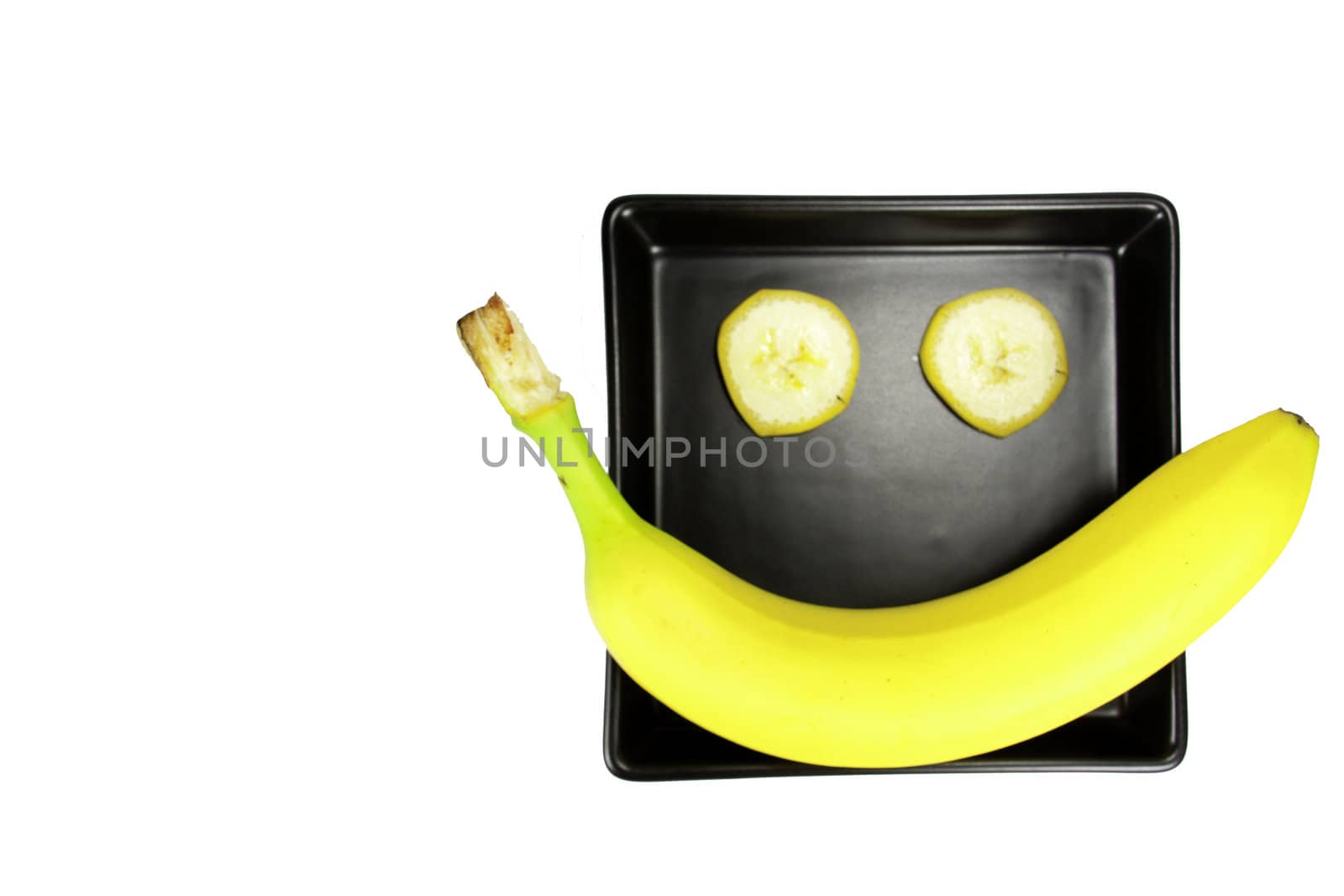 Picture of a banana on a black plate, arranged as smiling