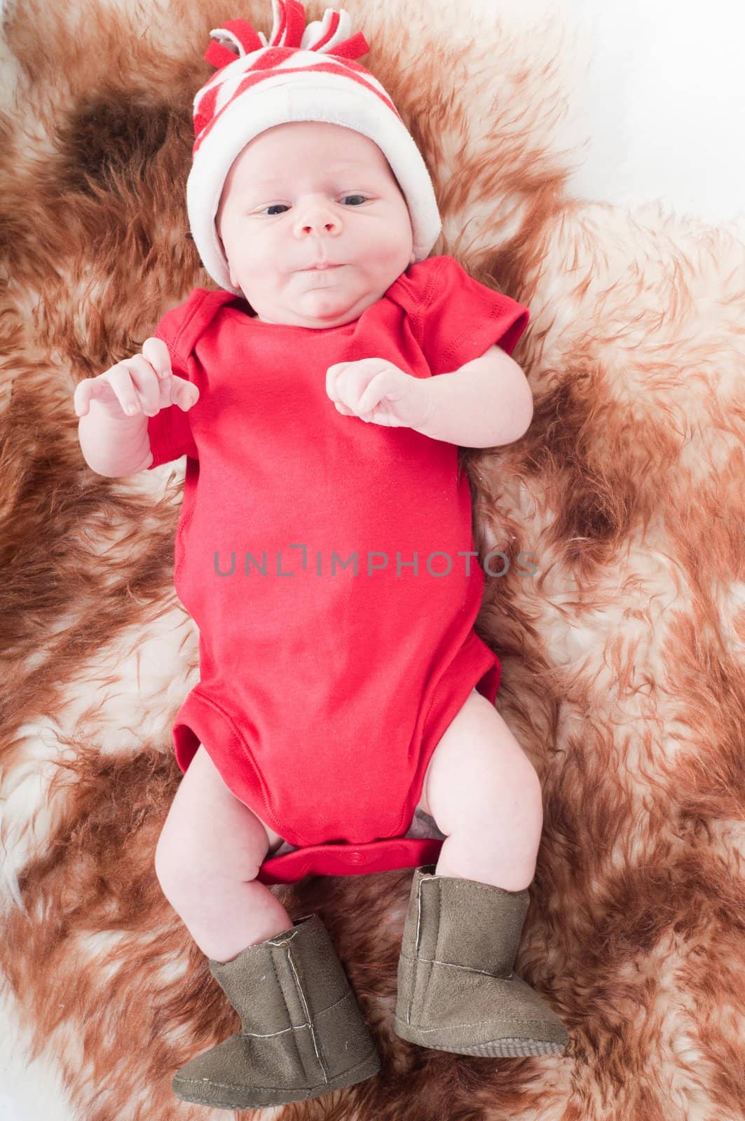 Newborn baby in chritstmas hat lies on fur