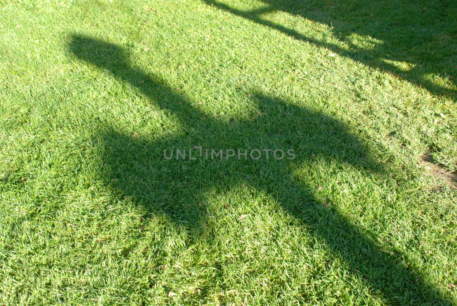 Warm long shadow of the cross fall into the green grass