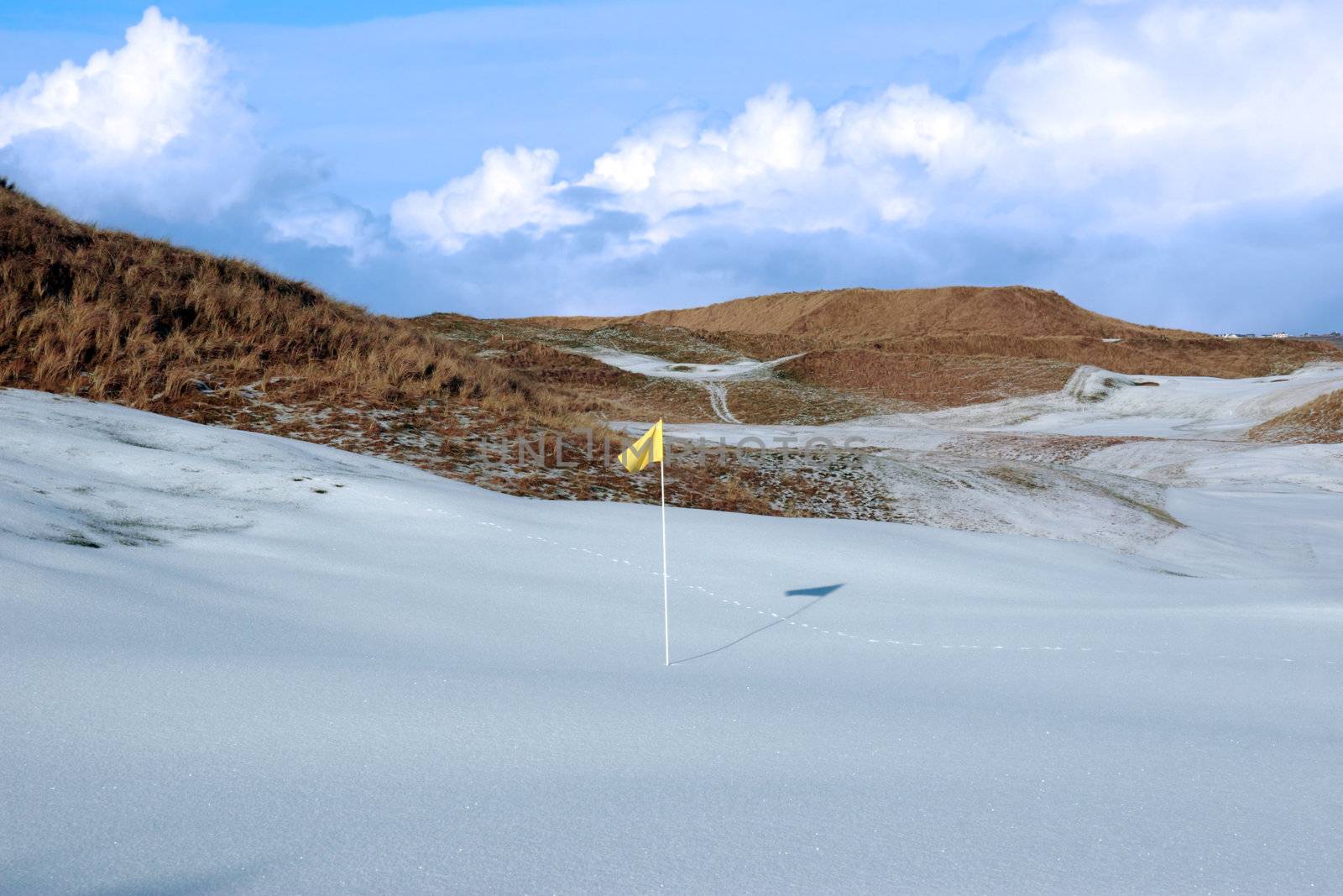 yellow flag on a snow covered links golf course in ireland in winter