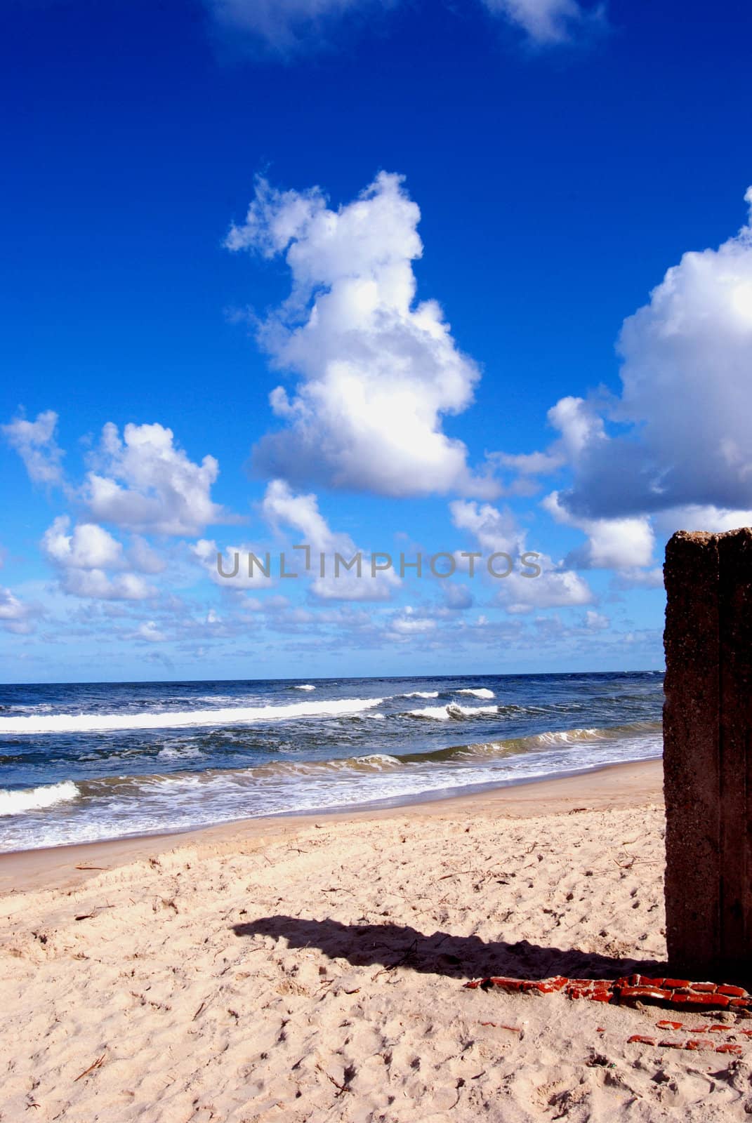 Summer morning cumulus over the sea and sandy coast with the object shadow