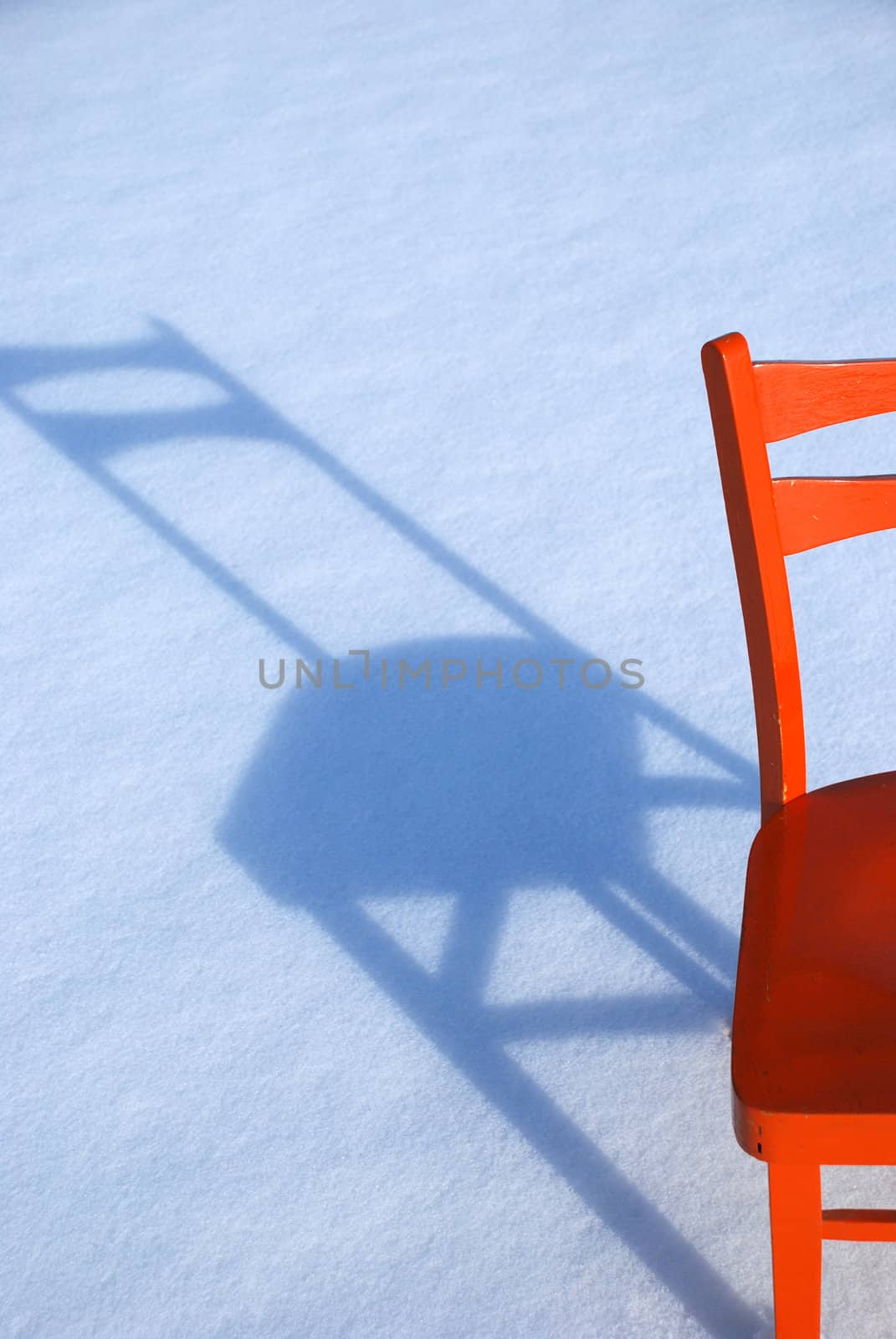 The orange chair and its shadow on the snow