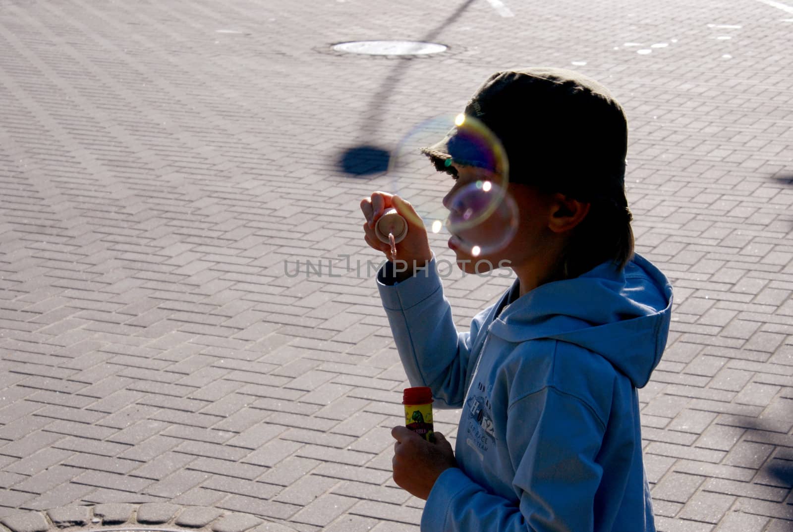 Kid in blue blowing big soap bubbles