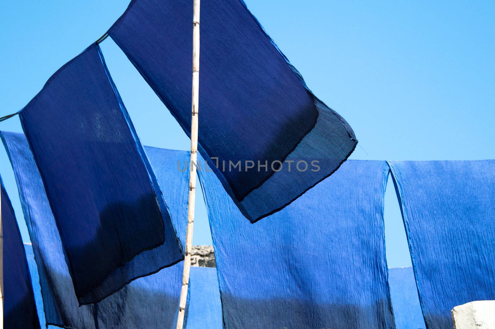 Blue dyed scarves drying in the sun against great blue sky in Morocco