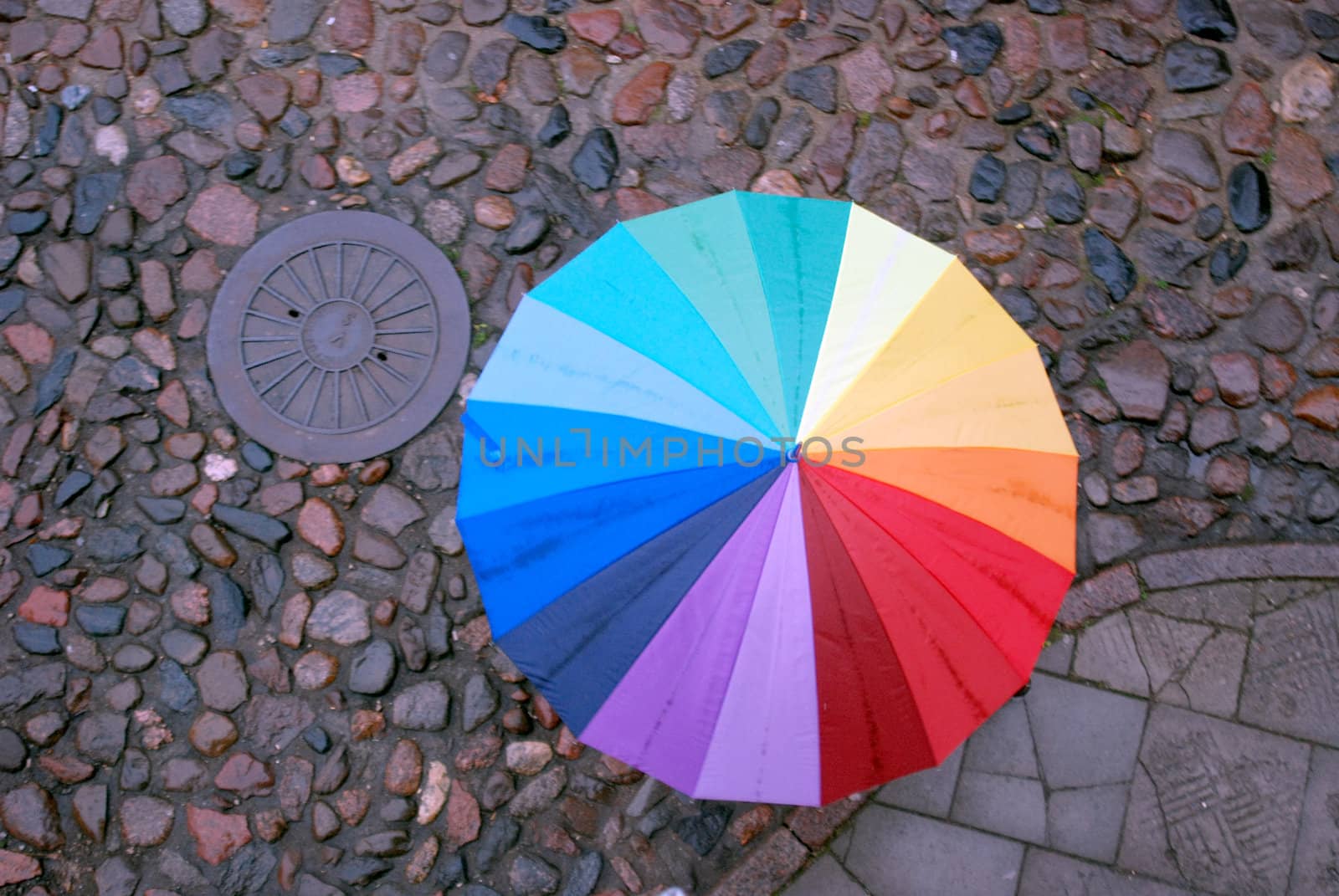 Rainbow-colored umbrella on the ancient stone pavement