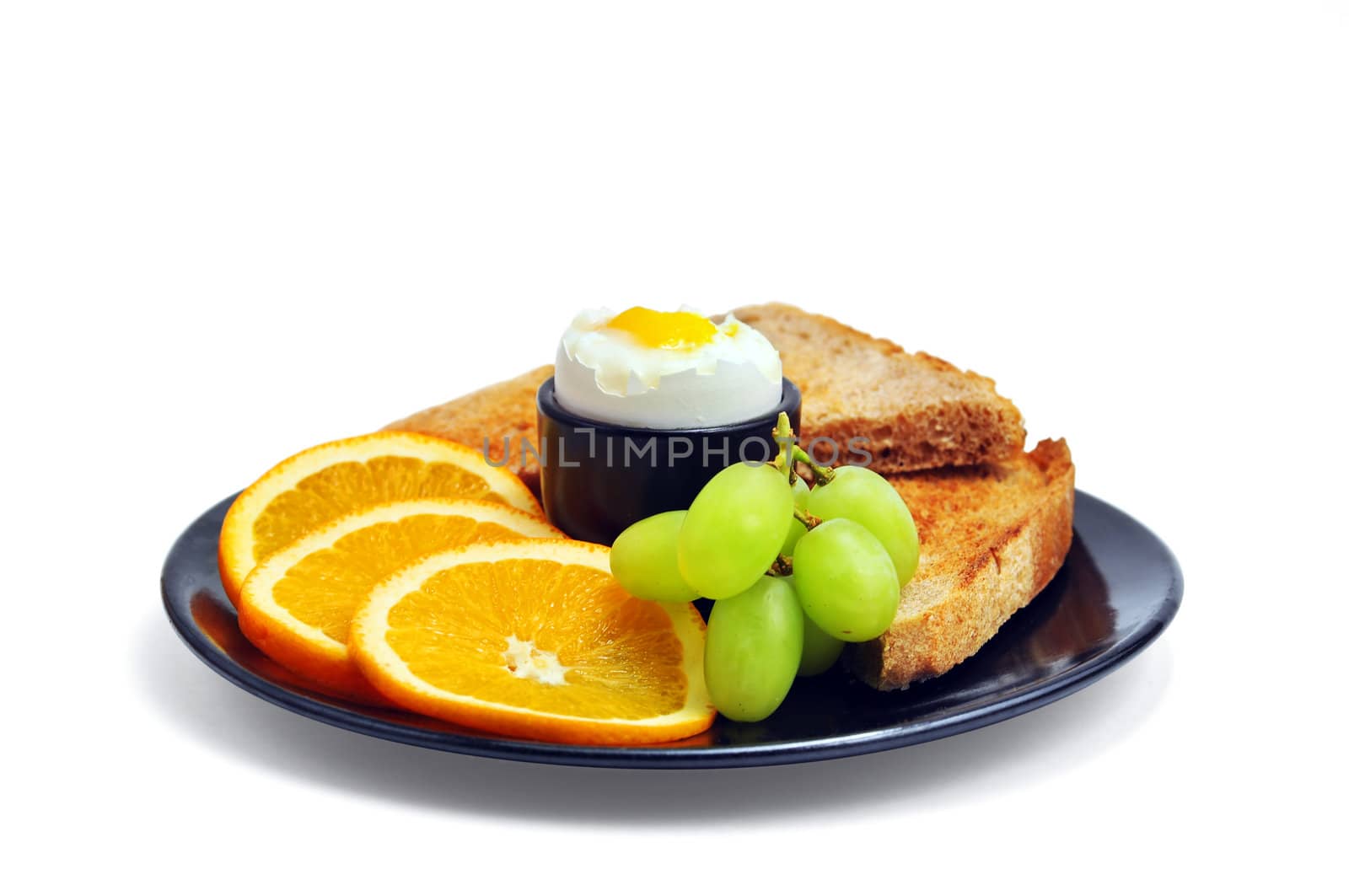 Perfect healthy breakfast: hard boiled egg, slices of oranges, green grapes and multigrain toasted bread.