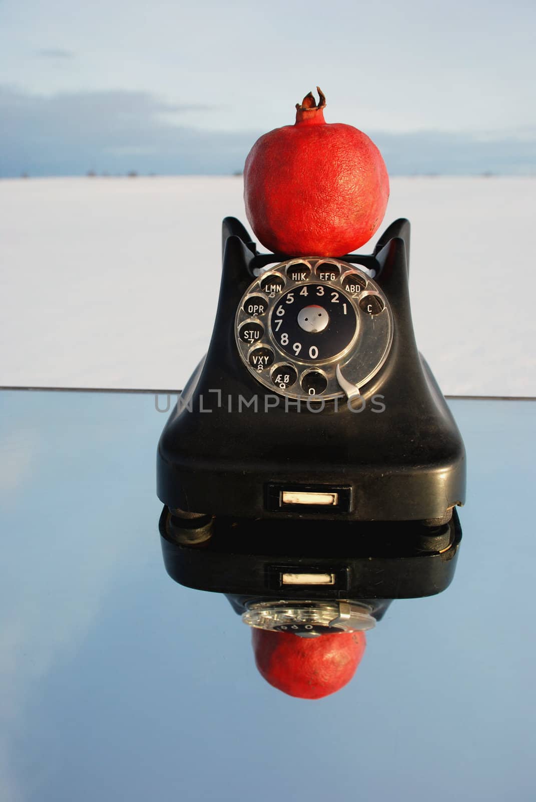 Black vintage phone on mirror with red pomegranate