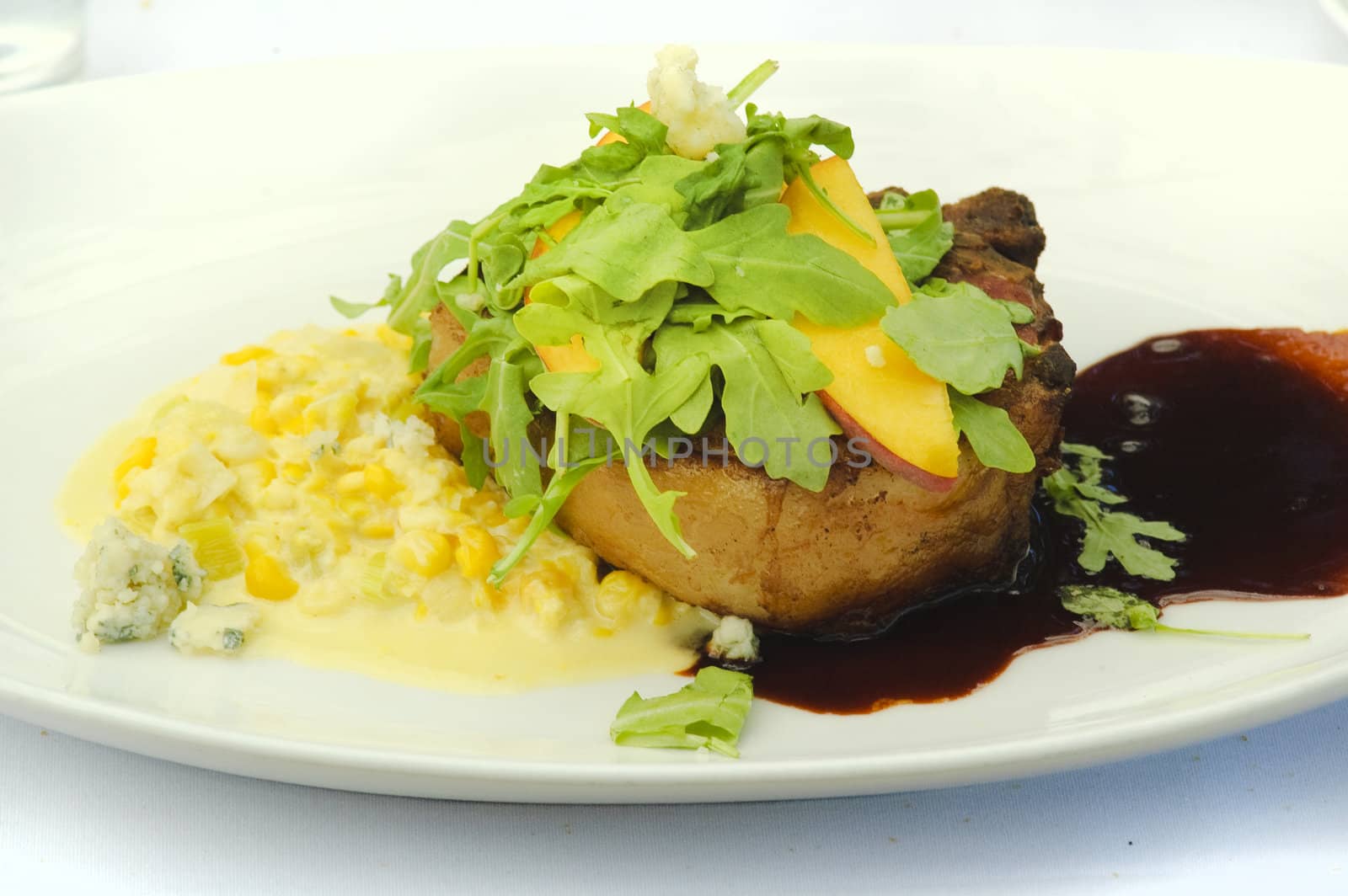 Meat dressed with greens, peach and a cherry sauce creamed corn and blue cheese
