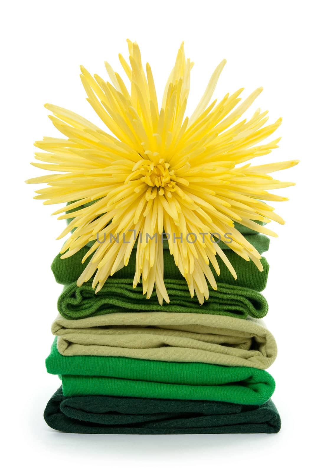 Fresh spring laundry. Yellow flower on top of green folded clothes.