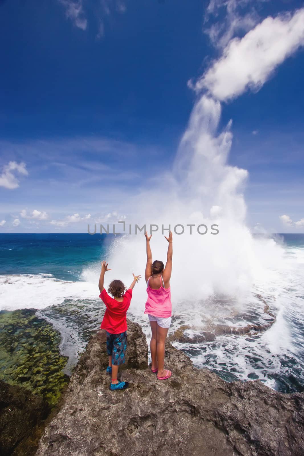 Two youngsters raise their arms as the blowholes put on a specatacular display at Houma on the western side of Tongatapu Island in the Pacific.