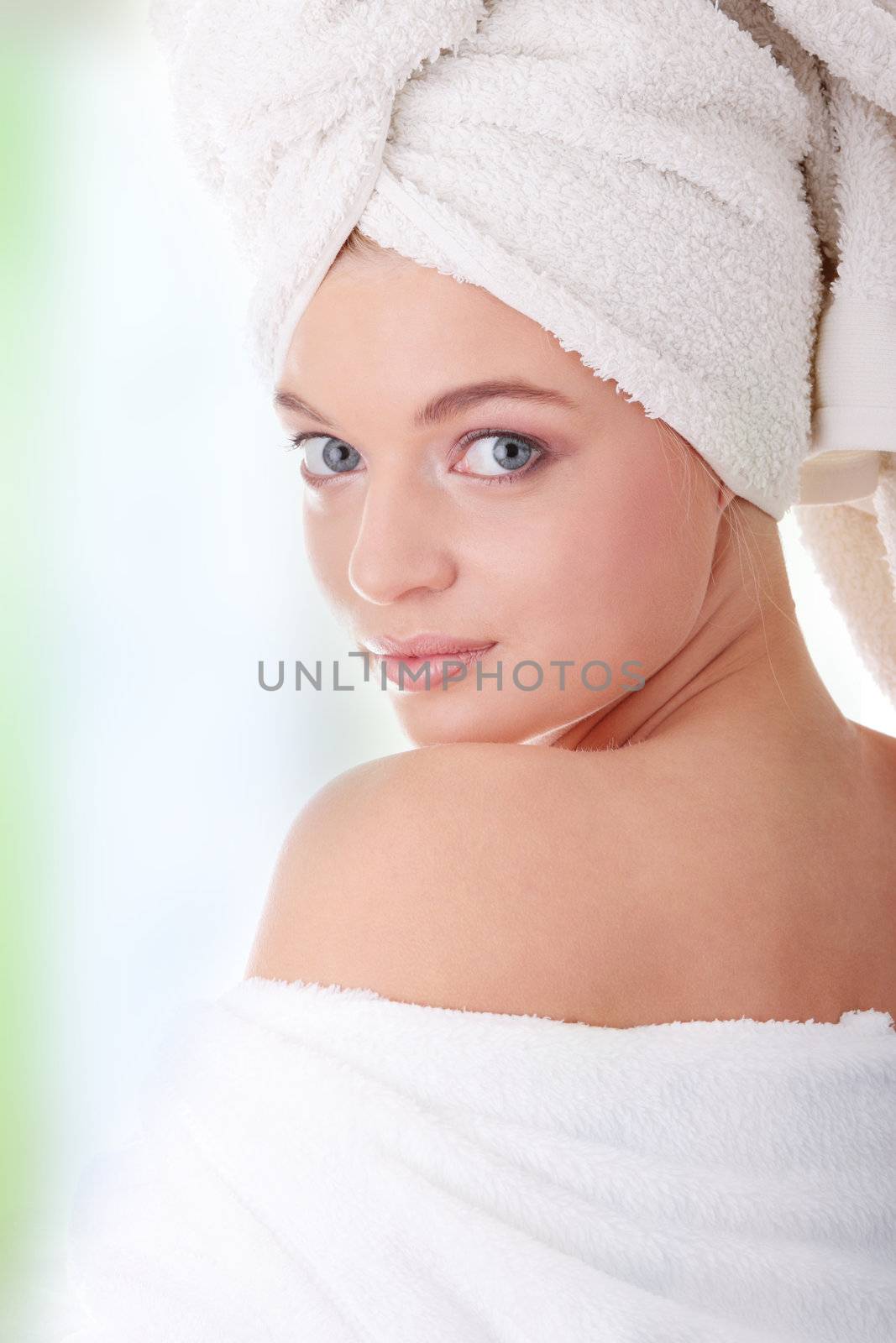 Young beautiful caucasian woman after bath, against abstract green background