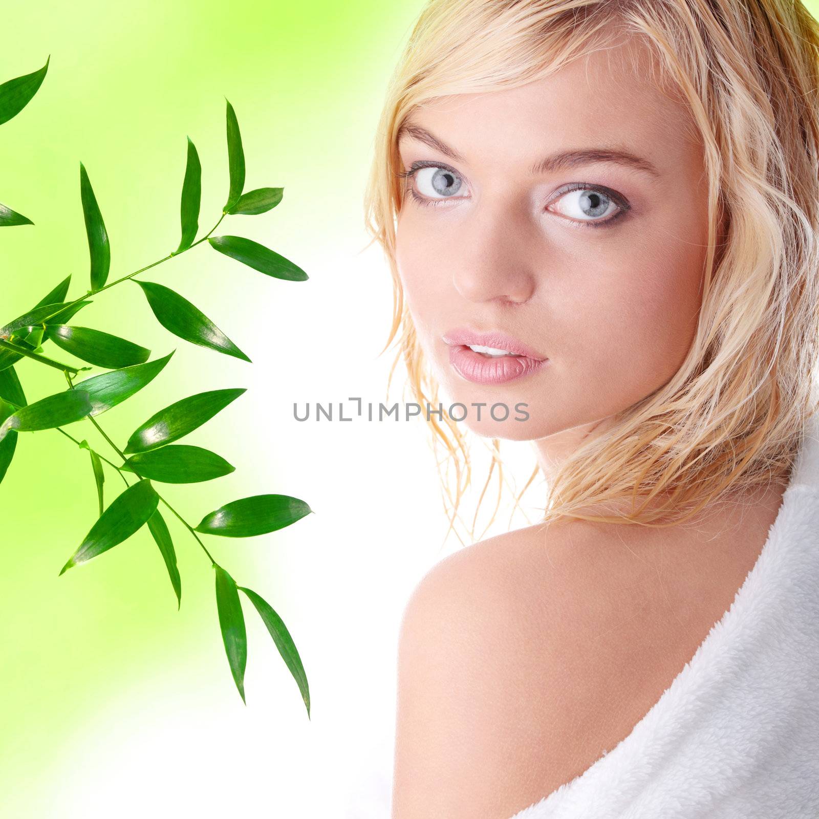 Young beautiful blond teen woman dressed in white bathrobe, against abstract green background