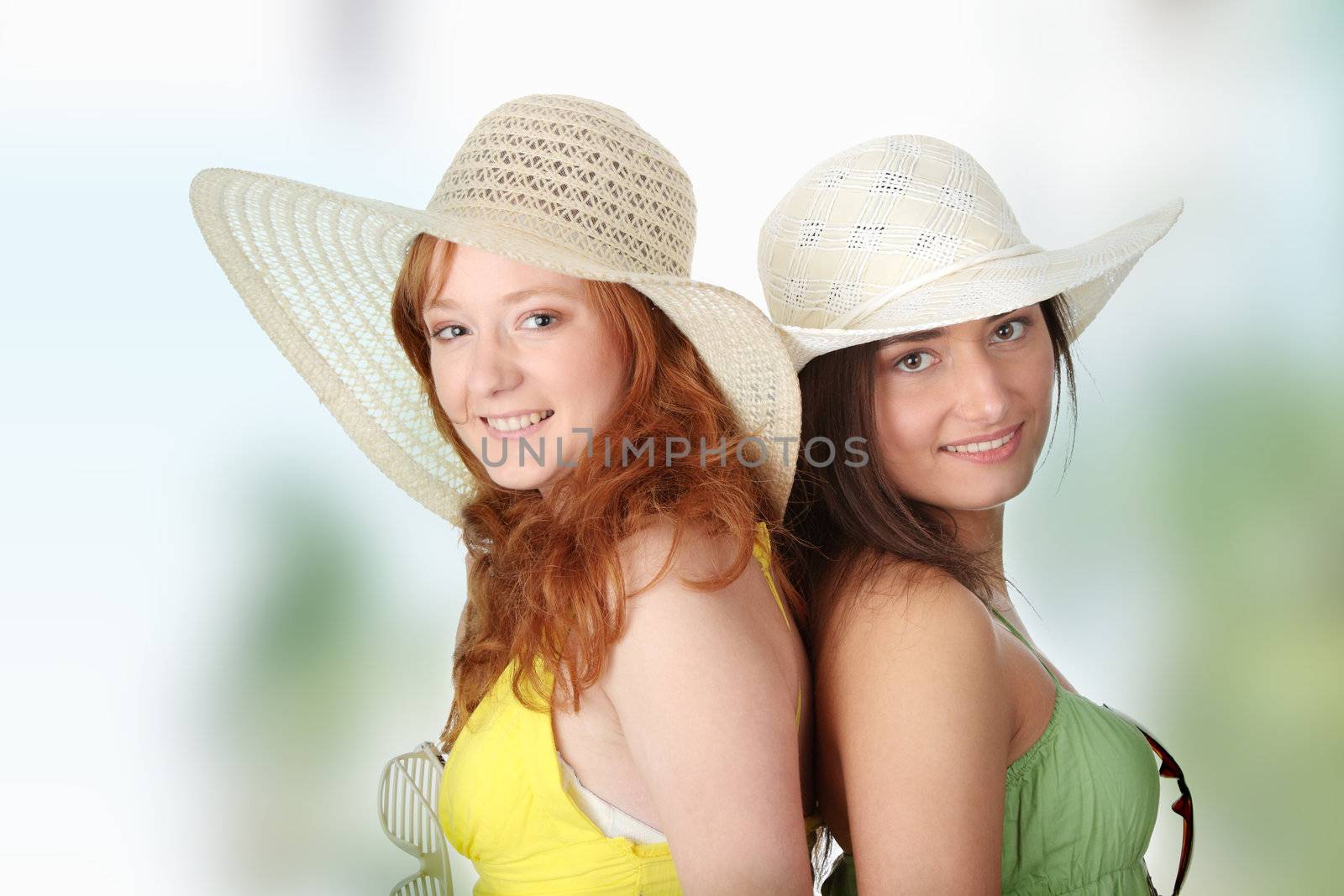 Two girlfriends in summer dress and hat over white background