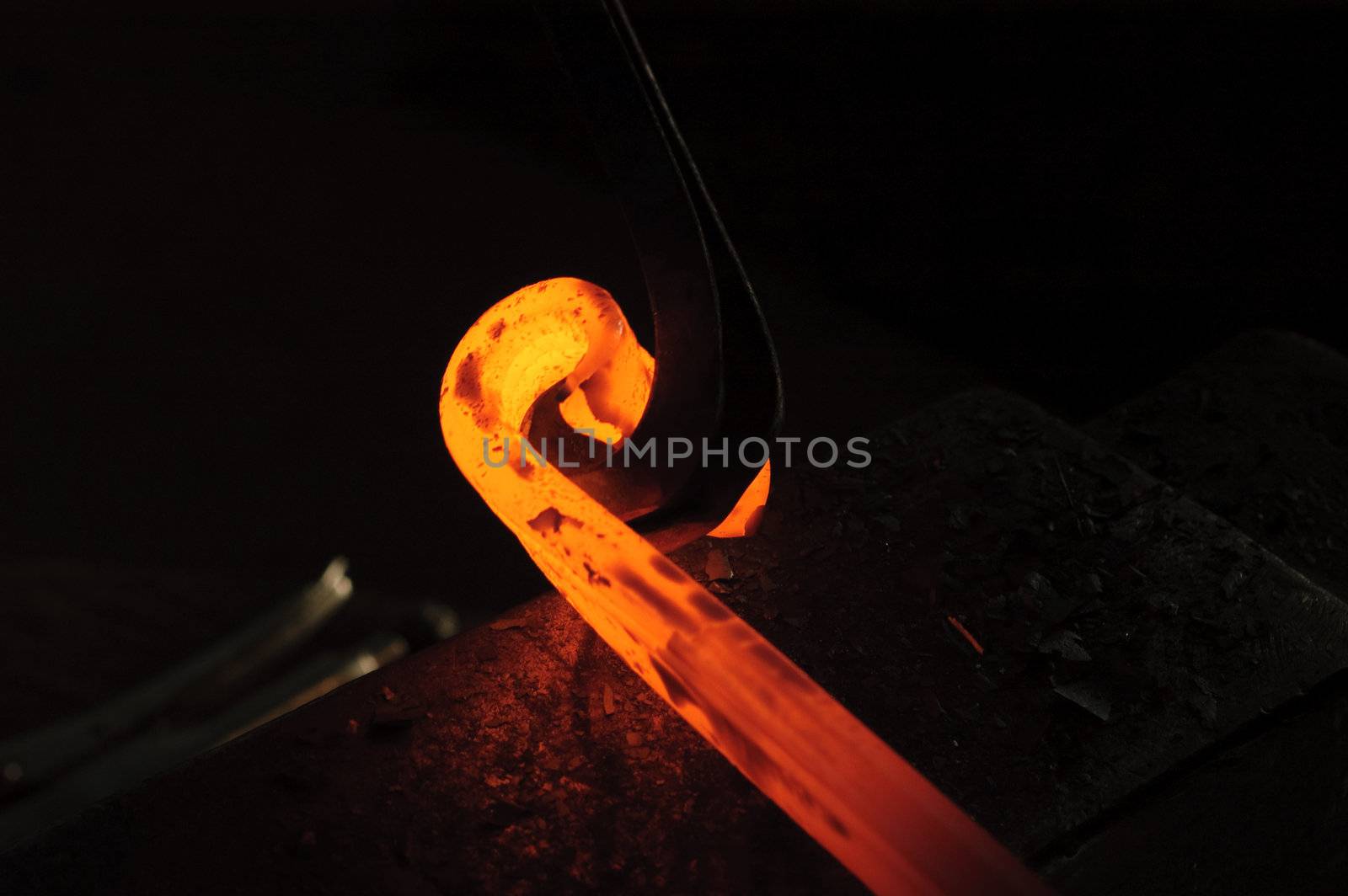 Blacksmith working on decorative handrail bending the heated metal