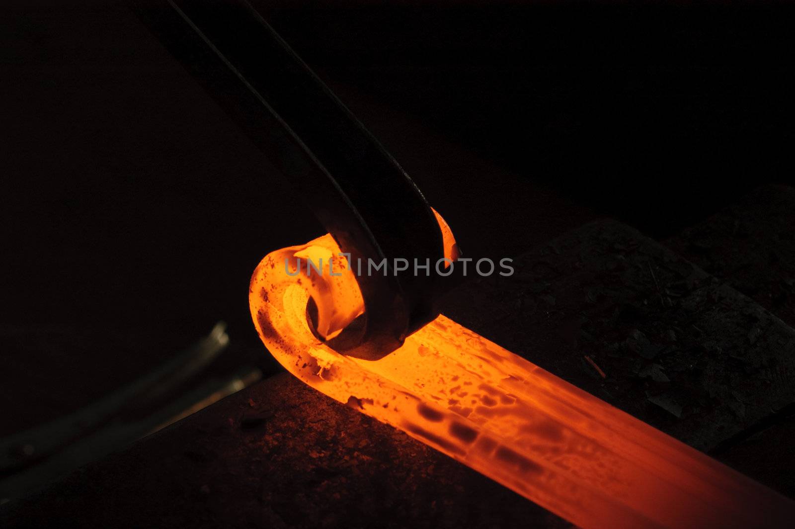 Blacksmith working on decorative handrail bending the heated metal