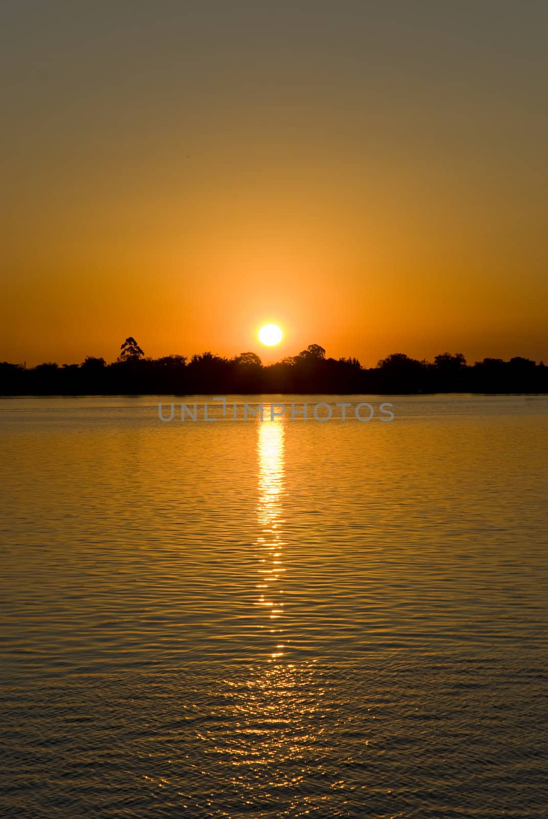 Sunset over a calm lake with deep orange hue. Lots of copy space.