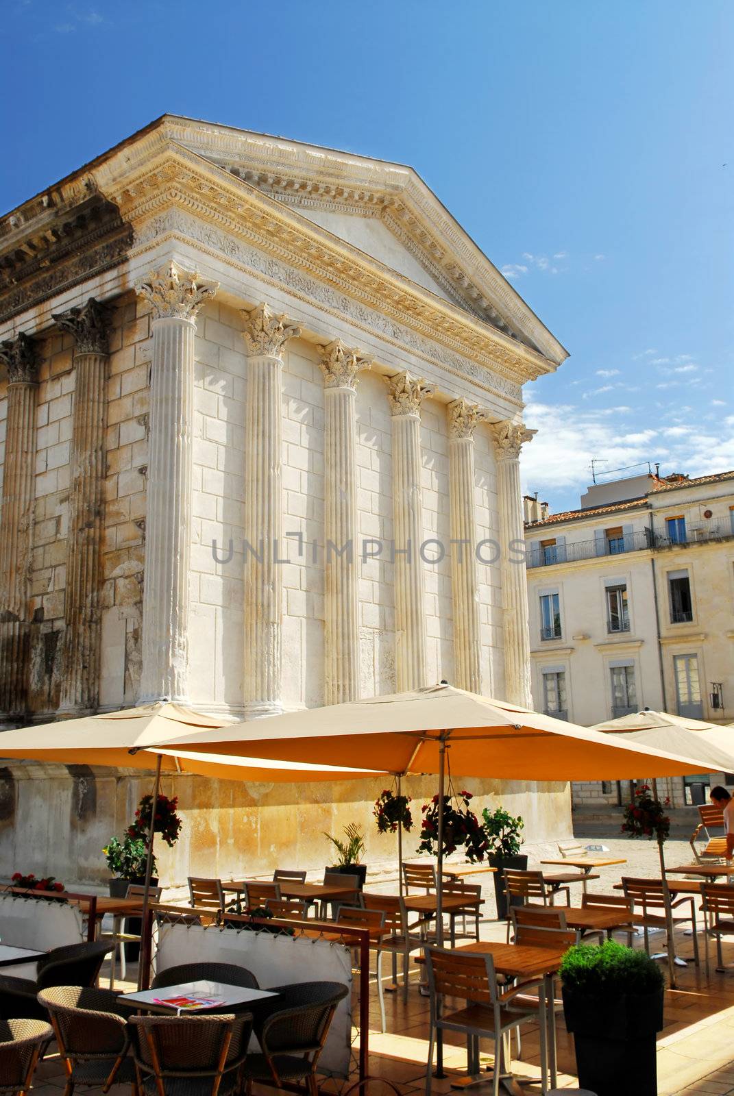 Roman temple Maison Carree and outdoor cafe in city of Nimes in southern France