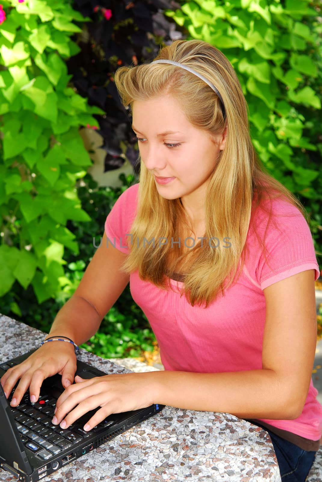 Teenage girl typing on a portable computer outside