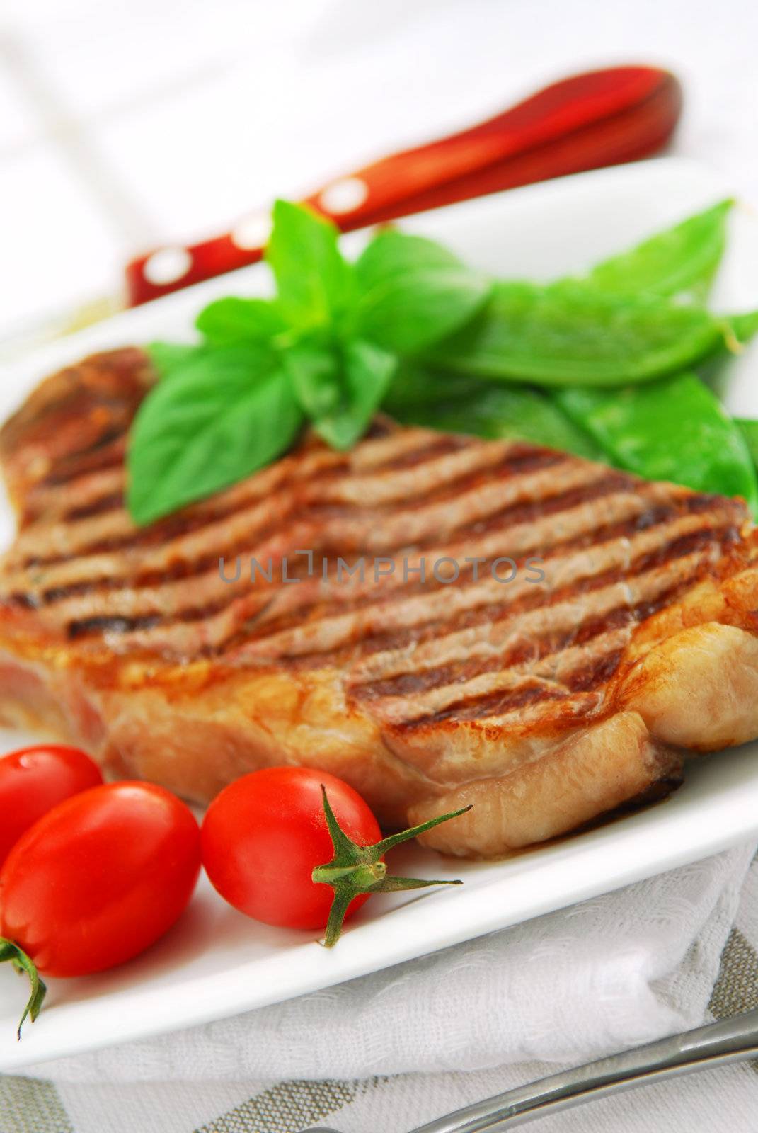 Grilled New York beef steak served on a plate with vegetables