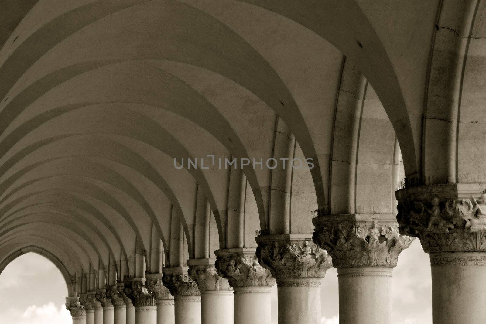Sepia-toned row of arches and columns in Venice Italy.

