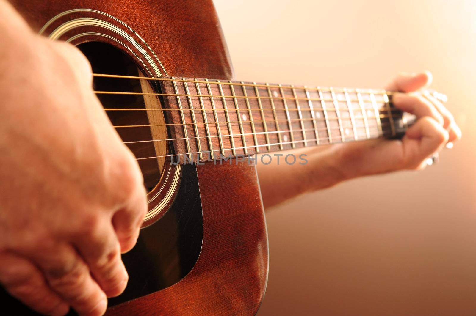 Hands of a person playing an acoustic guitar