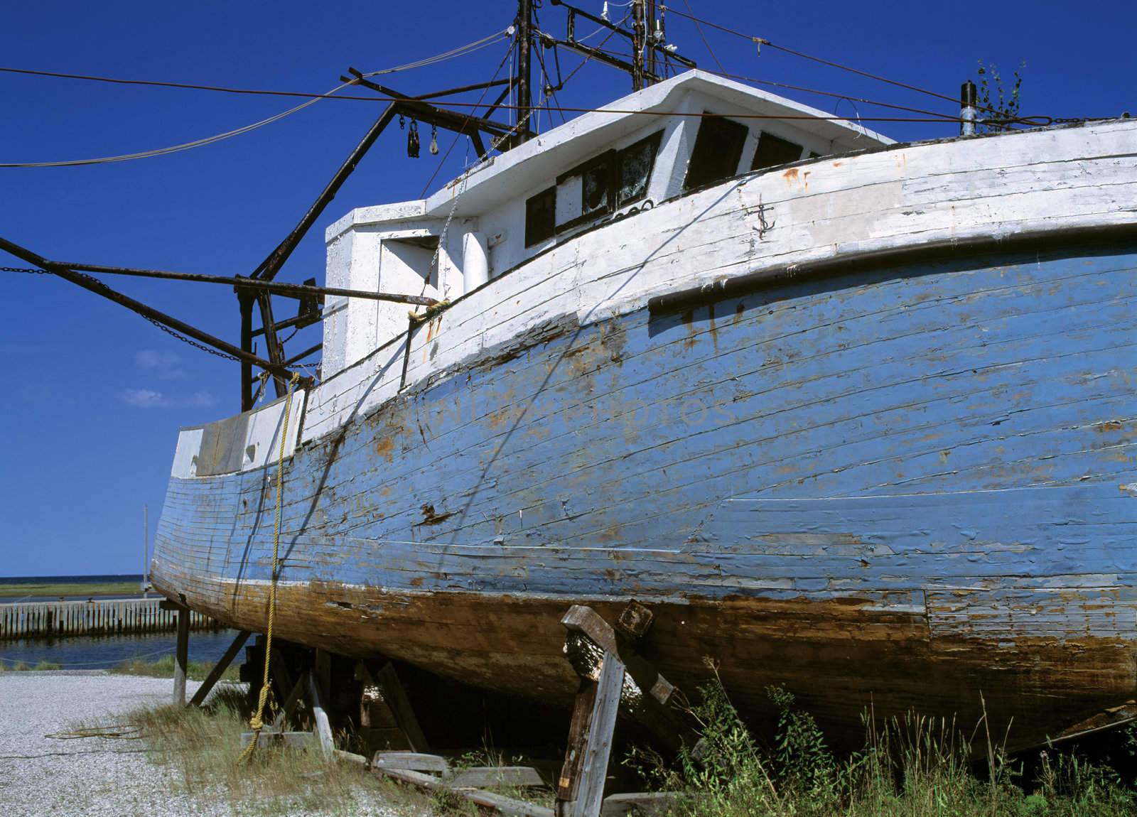 A damaged boat rotting away on the edge of the water. Scanned from film.
