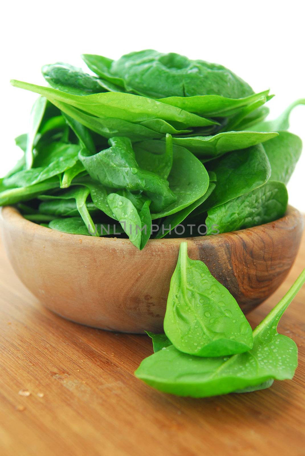 Fresh spinach iin a wooden bowl on a cutting board